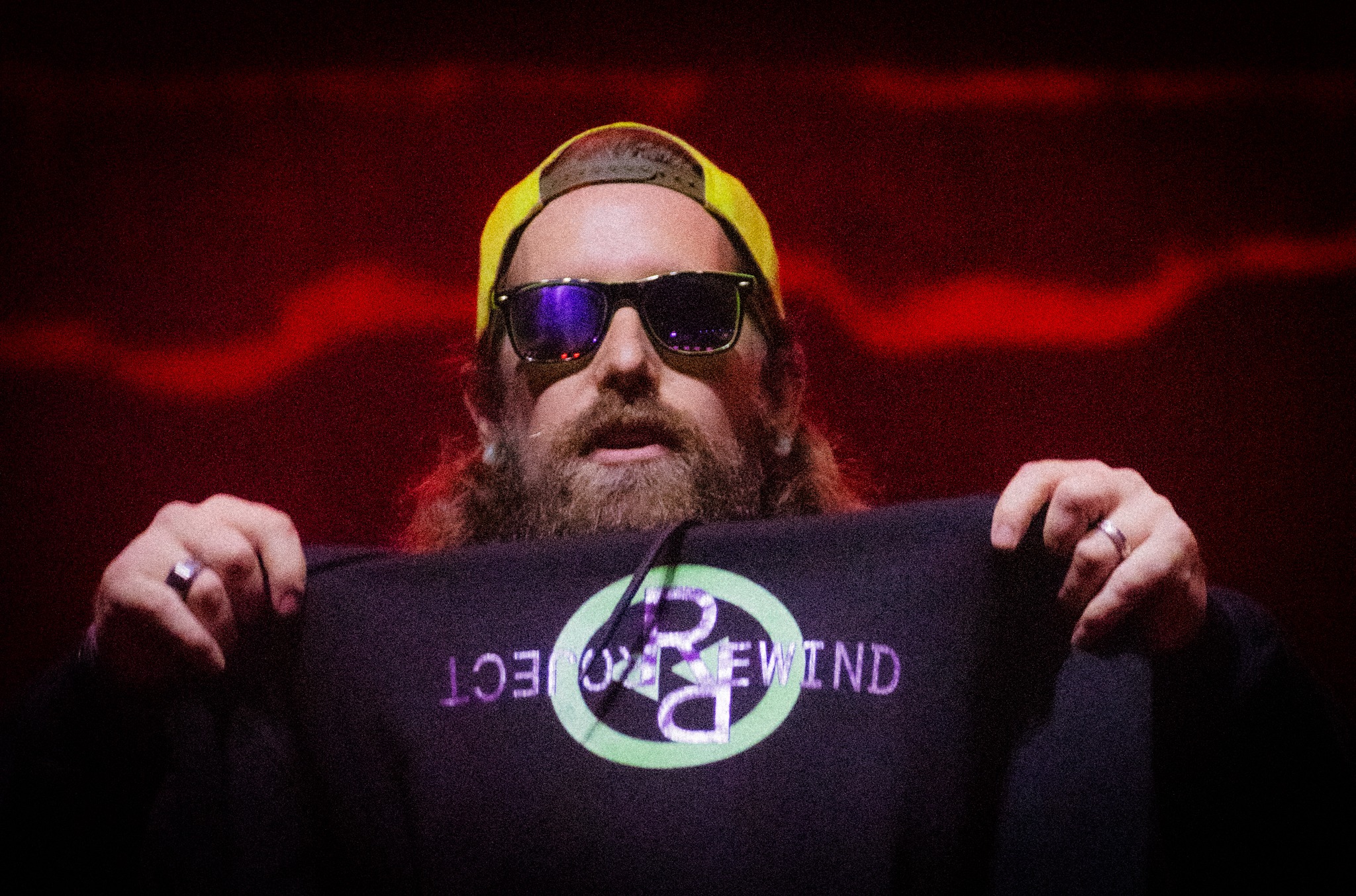 Brent holding up a Project Rewind tee on stage